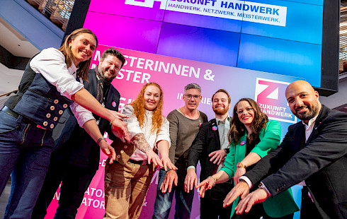 Junge dynamische Handwerker vor dem Logo des Kongress Zukunft Handwerk (Laola-Welle)