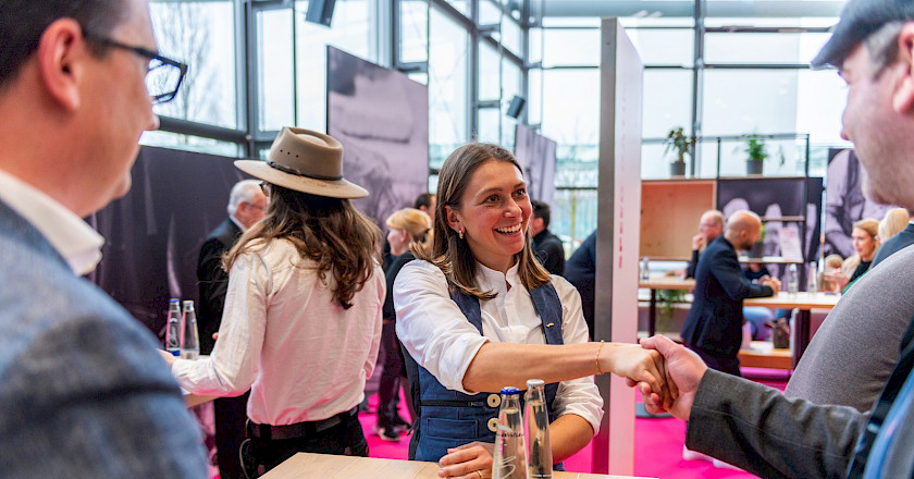 Begrüßung von Messebesuchern per Handschlag durch junge Handwerkerin Begrüßung von Messebesuchern per Handschlag durch junge Handwerkerin