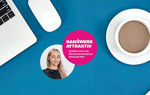 Schreibtisch mit Notebooktastatur, Kaffetasse, Frauenkopf und rosa Logo "Handwerk Attraktiv"